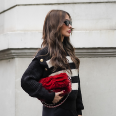 Woman with wavy brown hair and stripy jumper, holding a red clutch bag