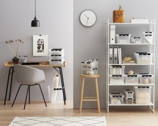 Organized home office with hairpin desk and office chair, and shelving unit filled with storage boxes and box files.