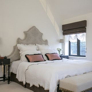 pillows on bed in master bedroom with white wall and window