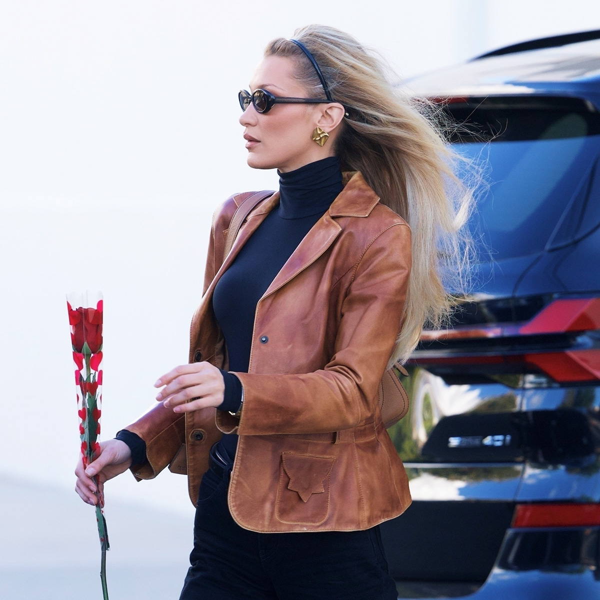 Bella Hadid wearing a brown leather jacket, black turtleneck, bootcut jeans, and block-heel boots