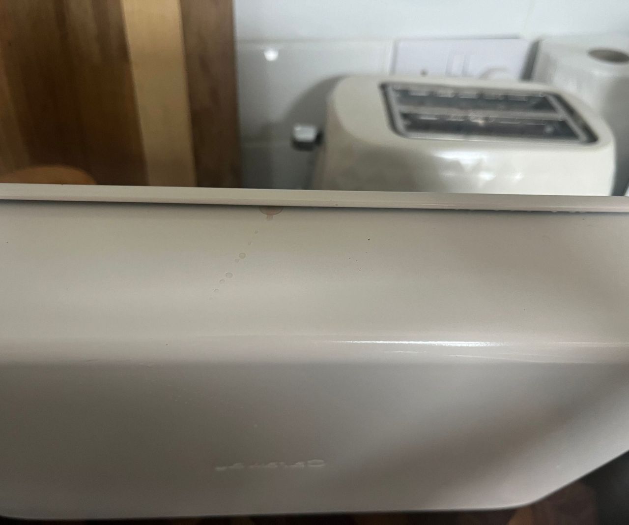 The edge of a cream baking tray with a drop of water leaking from the side