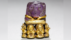 a purple amethyst carved into a lion's head and set on a base of gold baboons