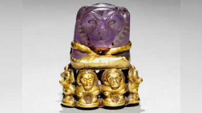 a purple amethyst carved into a lion's head and set on a base of gold baboons