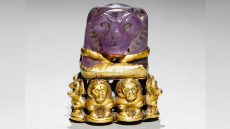 a purple amethyst carved into a lion's head and set on a base of gold baboons