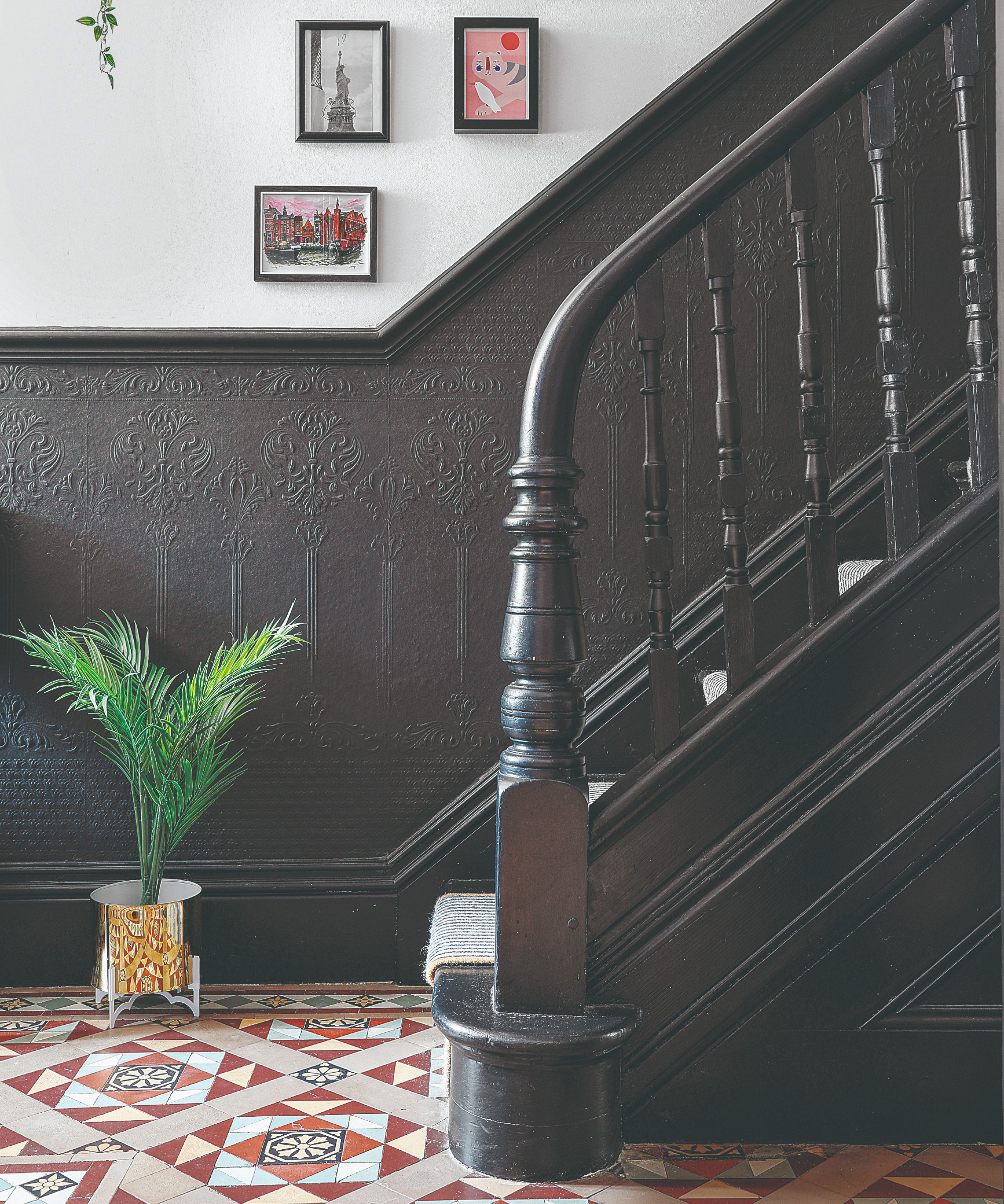 A hallway with a black-painted staircase and two-tone walls in black and white