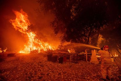 A firefighter aims water at California Mendocino Complex Fire