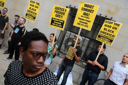 Demonstrators hold up signs outside the Freddie Gray hearing in Baltimore
