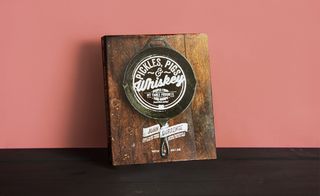 Front cover of the book 'Pigs, Pickles & Whiskey', rustic background and image, white lettering, dark wood surface, orange background