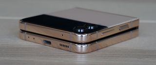 En Samsung Galaxy Z Flip 4 i en beige färg ligger stängd på ett bord, sett från en vinkel.
