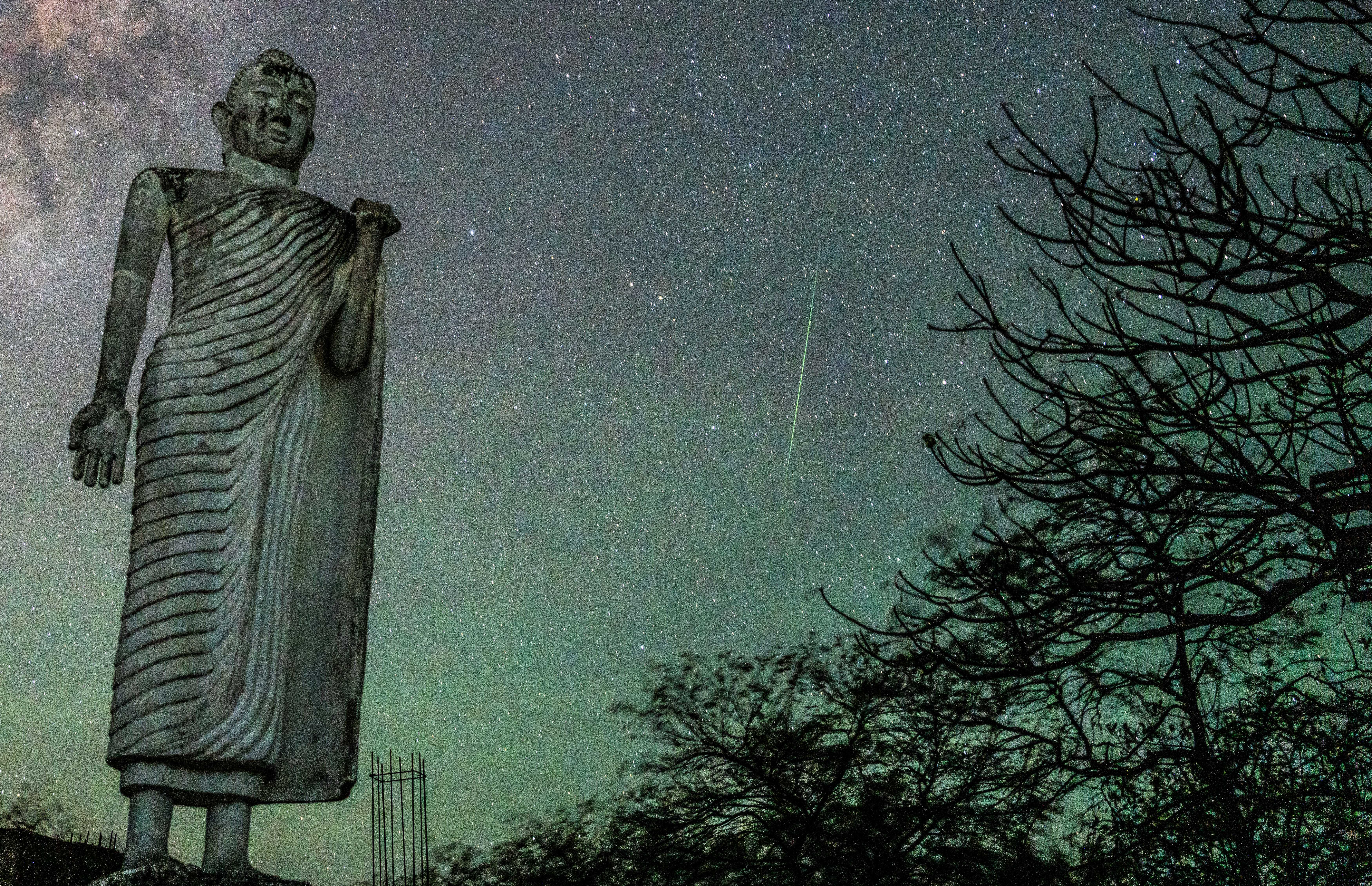 A Delta Aquariid meteor is appearing over the Buddha statue in Kantale, Sri Lanka, on July 4, 2024. In the tranquil nights of July, the sky is becoming a celestial theater. The Milky Way is stretching across like a shimmering river, Jupiter is gleaming brightly in the southeast, and Saturn is gracing the southwestern horizon with its majestic rings. Shooting stars from the Delta Aquariids meteor shower are adding brief, dazzling streaks to the canvas of the night. Constellations like Sagittarius and Scorpius are telling their own ancient stories against the backdrop of a summer night sky. (Photo by Thilina Kaluthotage/NurPhoto via Getty Images)