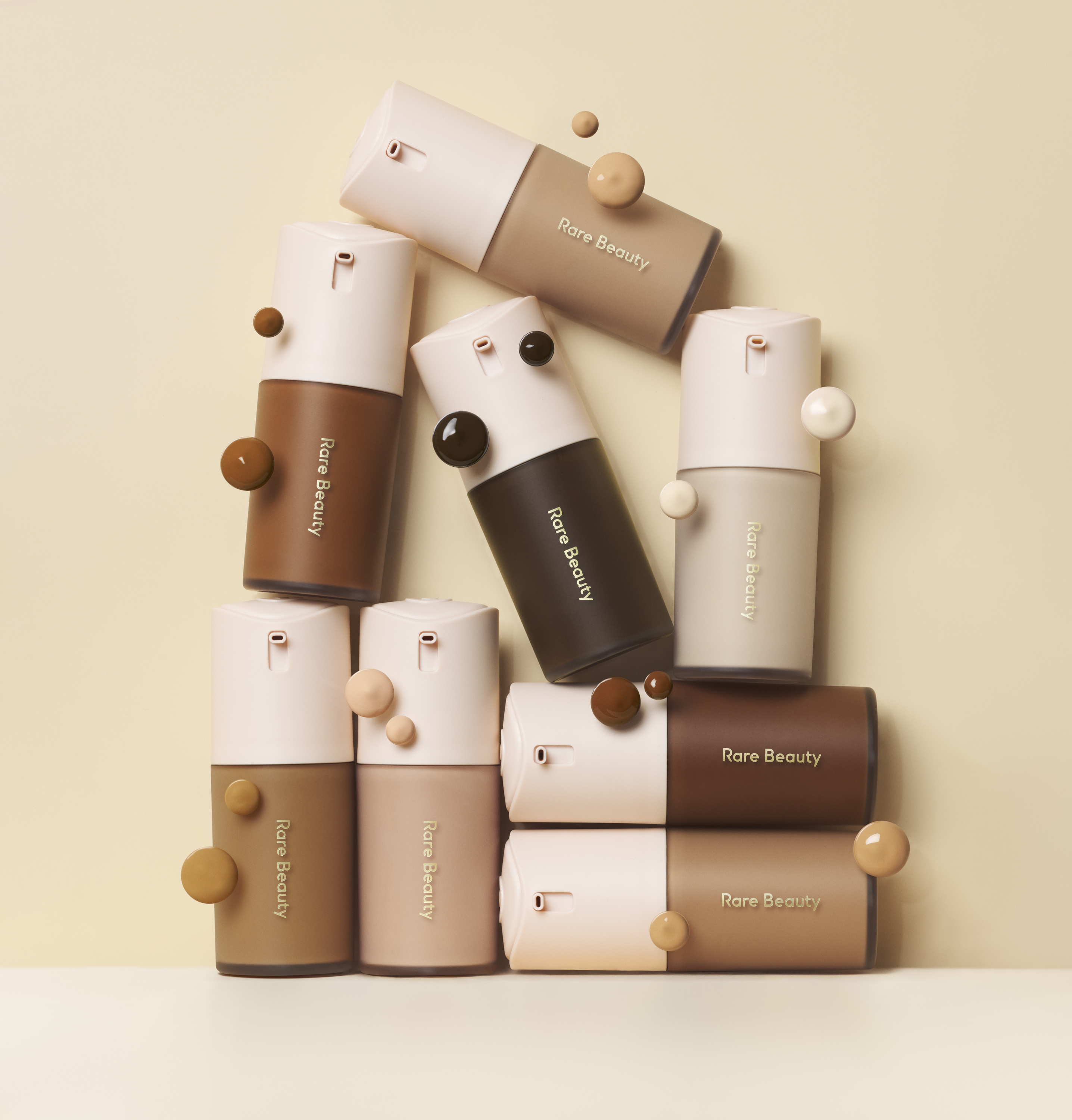 an assortment of foundation bottles with pink tops on a cream background