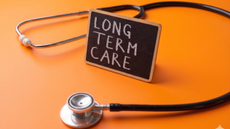 Picture of a stethescope and a small sign saying "LONG TERM CARE" on an orange background.