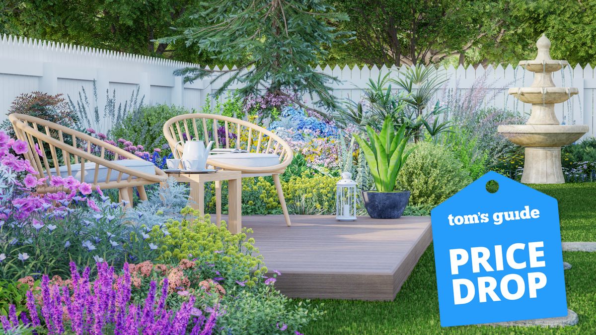 Garden furniture on decking on a lawn surrounded by flowers