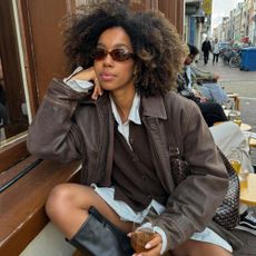 Influencer @amaka.hamelijnck wears a brown cardigan with a brown leather jacket and black boots.