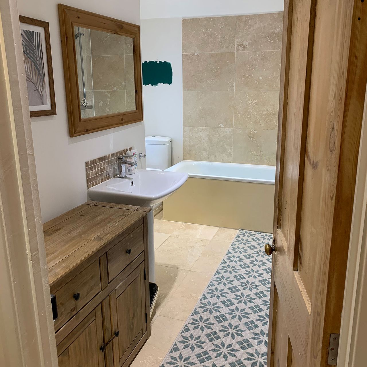 Small bathroom with patterned runner, wooden cabinet and built-in bath