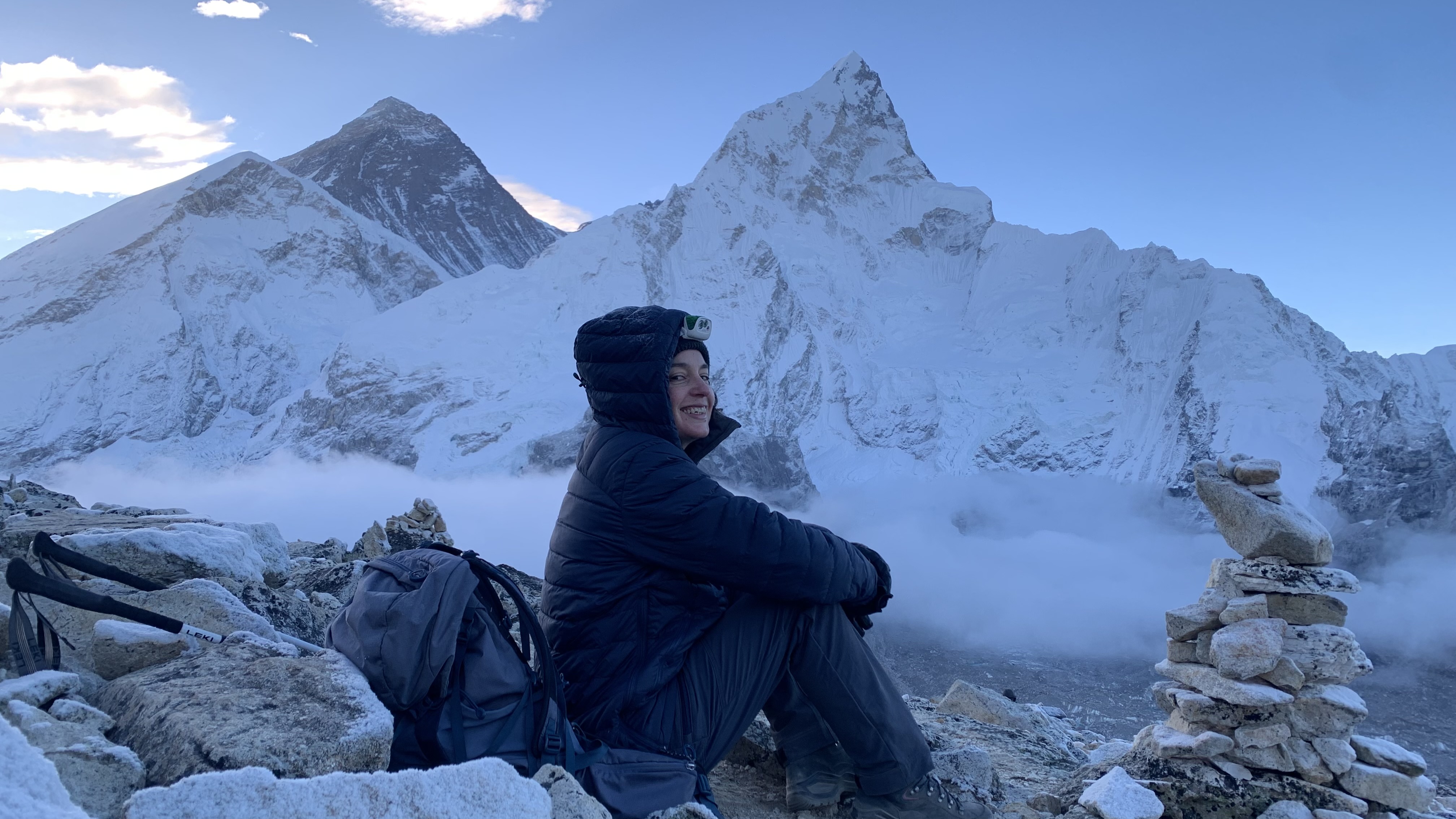 Julia Clarke sitting down at sunrise on Kala Patthar with Everest in the background