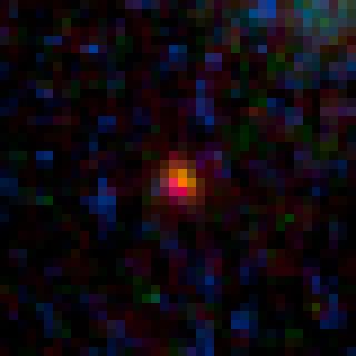 This close-up view shows the galaxy MACS0647-JD, the farthest object yet known, as it appears through a gravitational lens imaged by the Hubble Space Telescope. The galaxy is 13.3 billion light-years from Earth and formed 420 million years after the Big Bang.