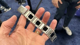 En hånd holder et sølvfarvet BHeart Smart-bånd op på CES-messen.