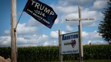 A sign for Trump 2024 in Hawkeye, Iowa, next to an anti-abortion sign with a cross nailed to it