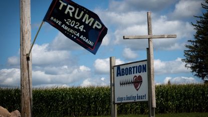 A sign for Trump 2024 in Hawkeye, Iowa, next to an anti-abortion sign with a cross nailed to it