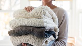 Woman holding stack of folded sweaters