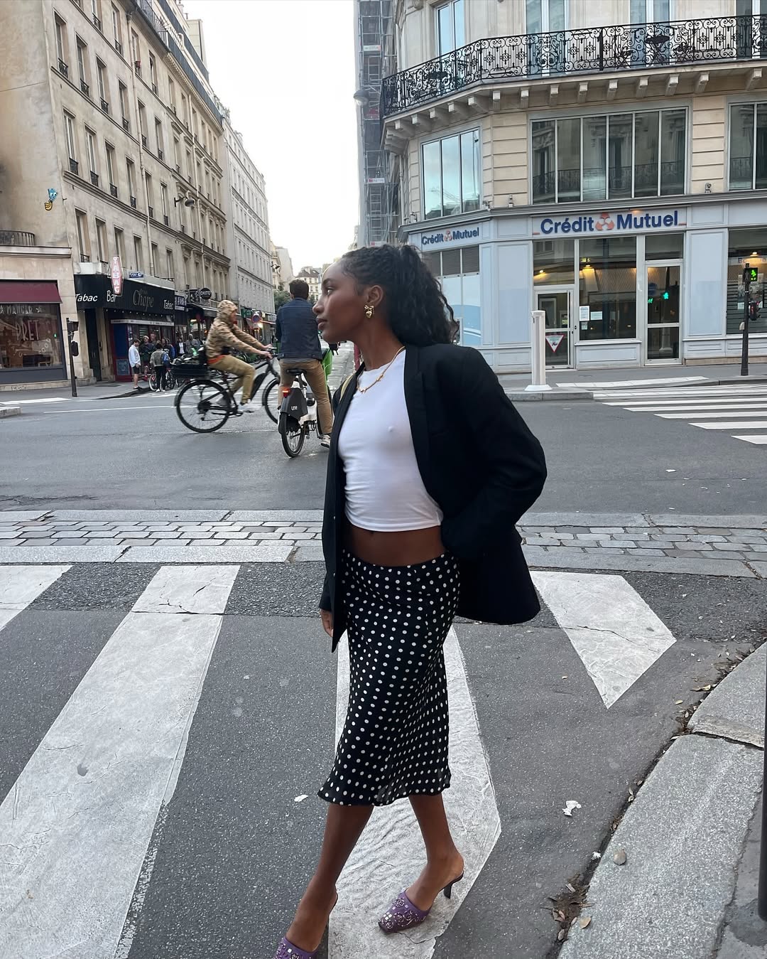 @rayan.xasan wears a black-and-white polka dot skirt with a white t-shirt, black blazer and purple mules