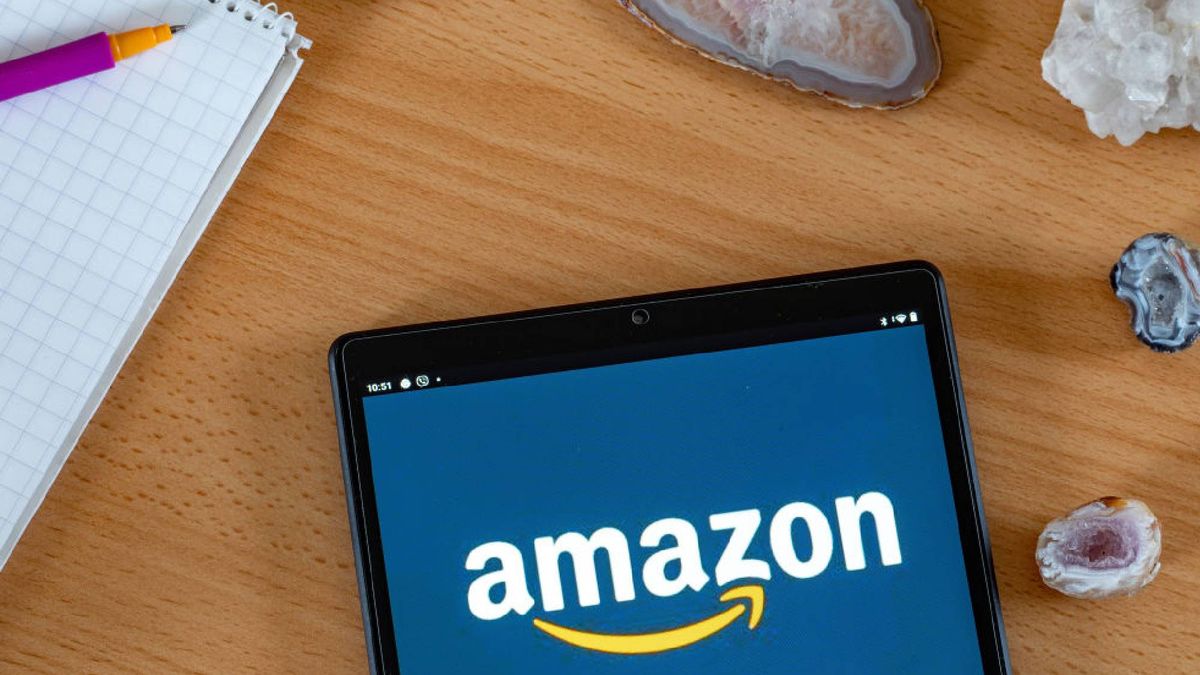 Amazon tablet on a wooden table next to a pen and notepad