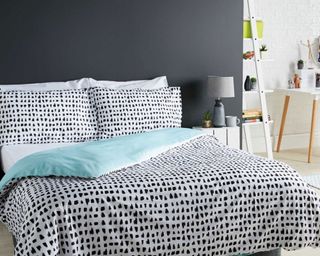 bedroom with black spotted bedlinen and wooden flooring