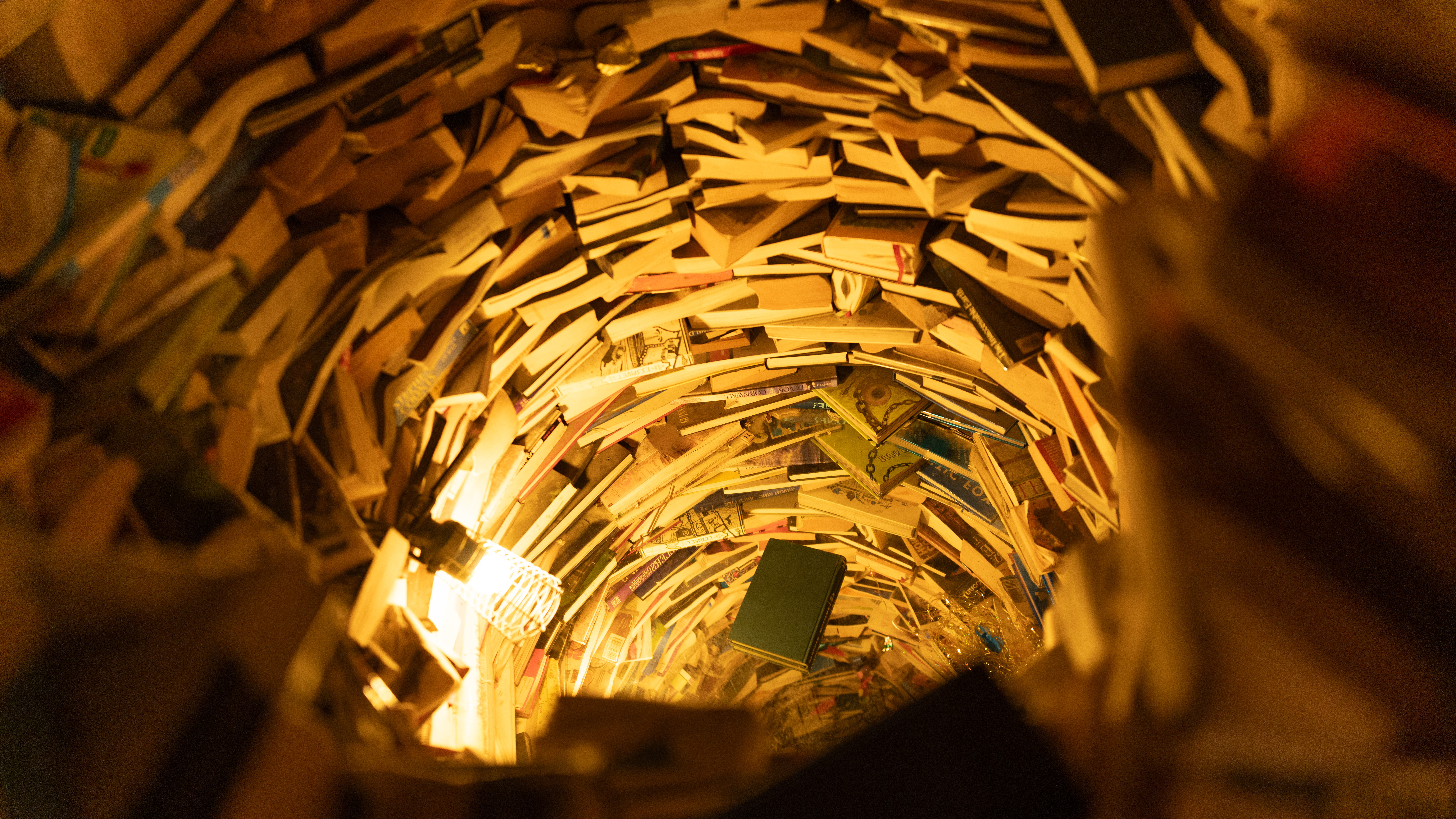 Image of an optical illusion in a theme park, where a series of books is arranged to look like an infinite tunnel.
