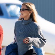 Bella Hadid arrives at the airport wearing grey leggings with a matching grey knit and black knee-high boots.