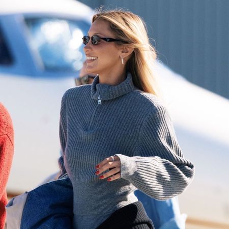 Bella Hadid arrives at the airport wearing grey leggings with a matching grey knit and black knee-high boots.