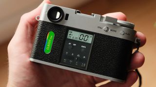 Fujifilm X Half camera held in a hand showing the film camera mode