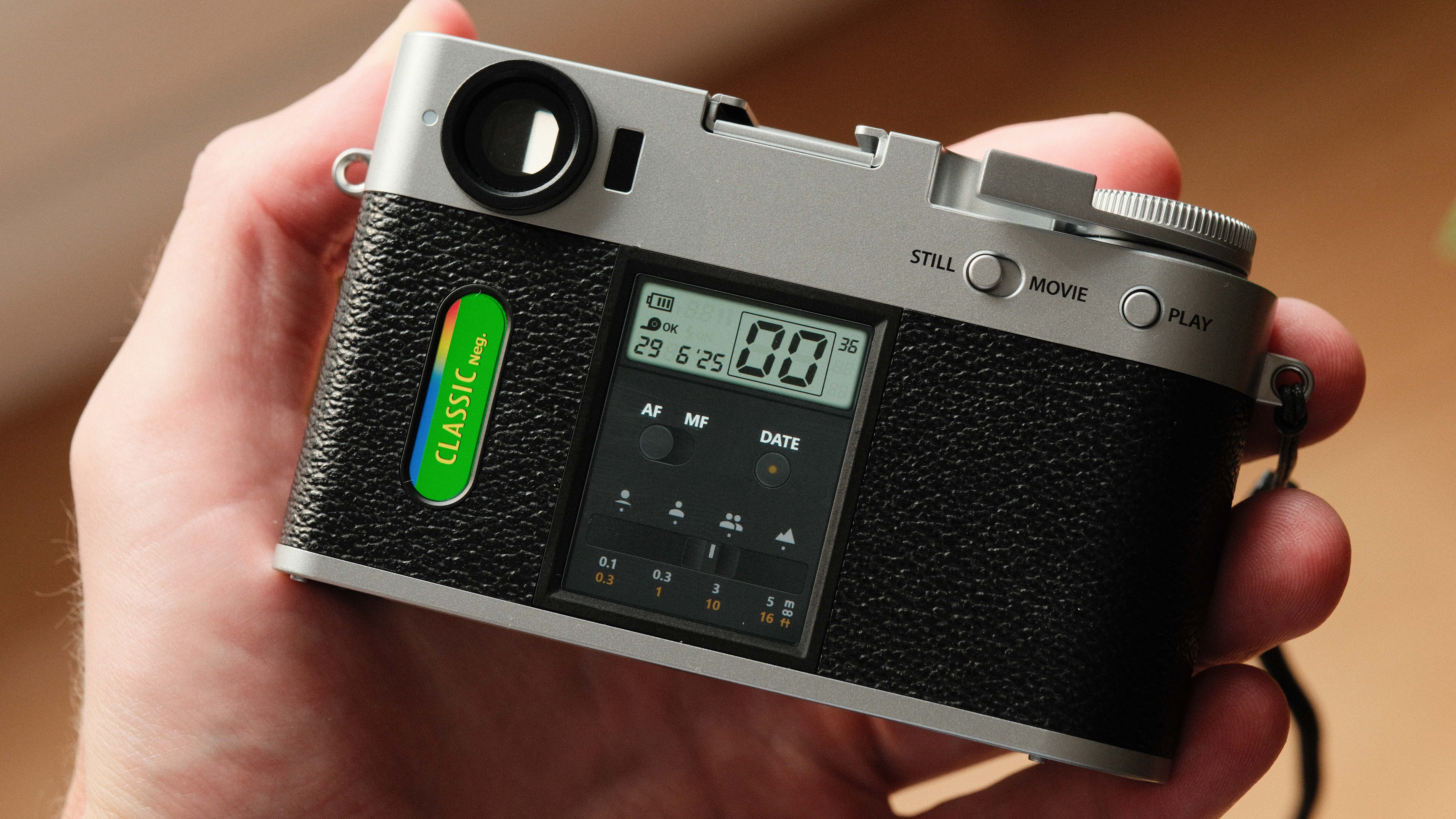 Fujifilm X Half camera held in a hand showing the film camera mode