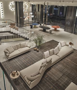 The showroom's ground floor seen from above with a large white sectional sofa taking the middle space
