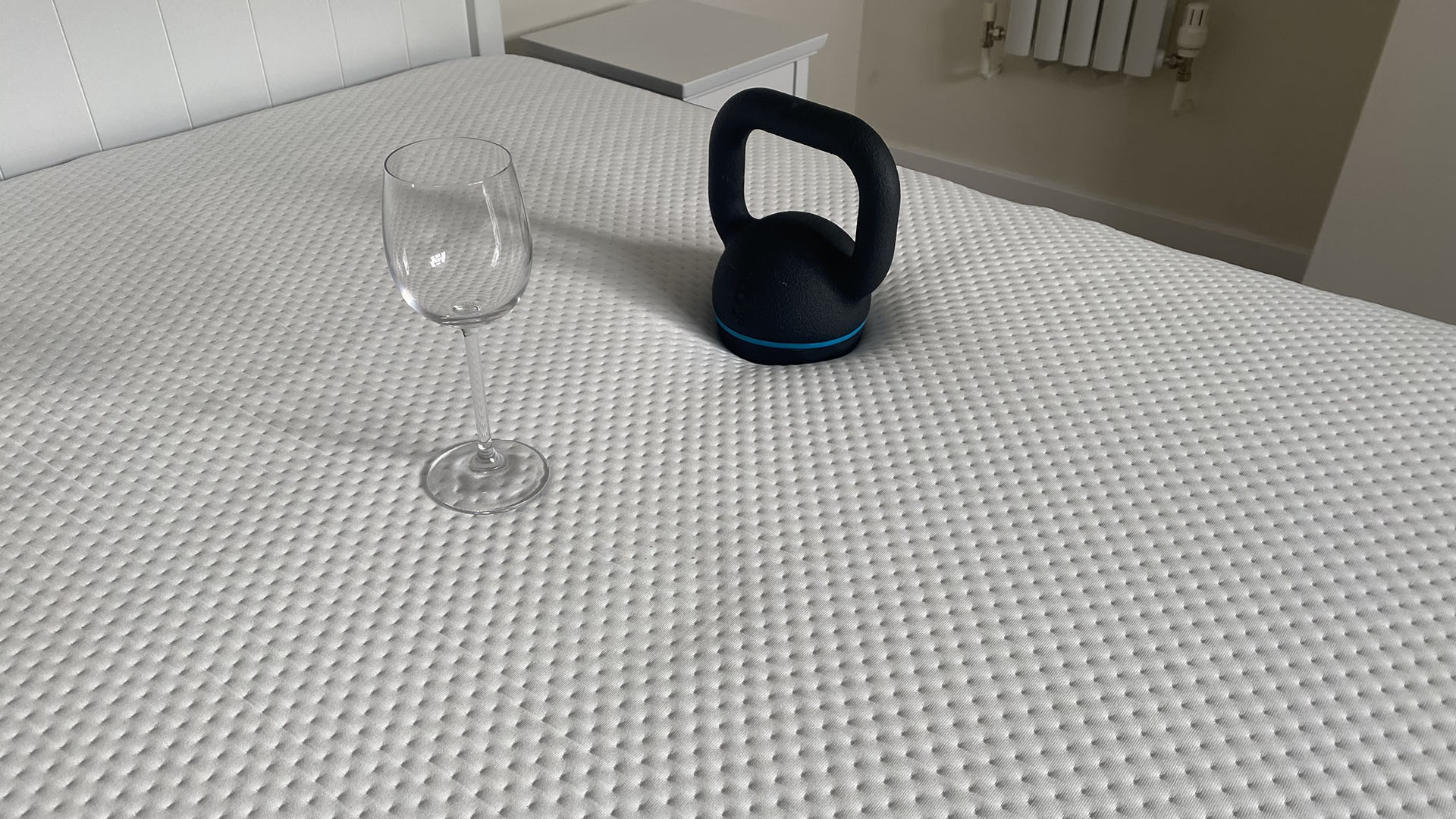 Otty Original Hybrid mattress with a weight and a wine glass on it