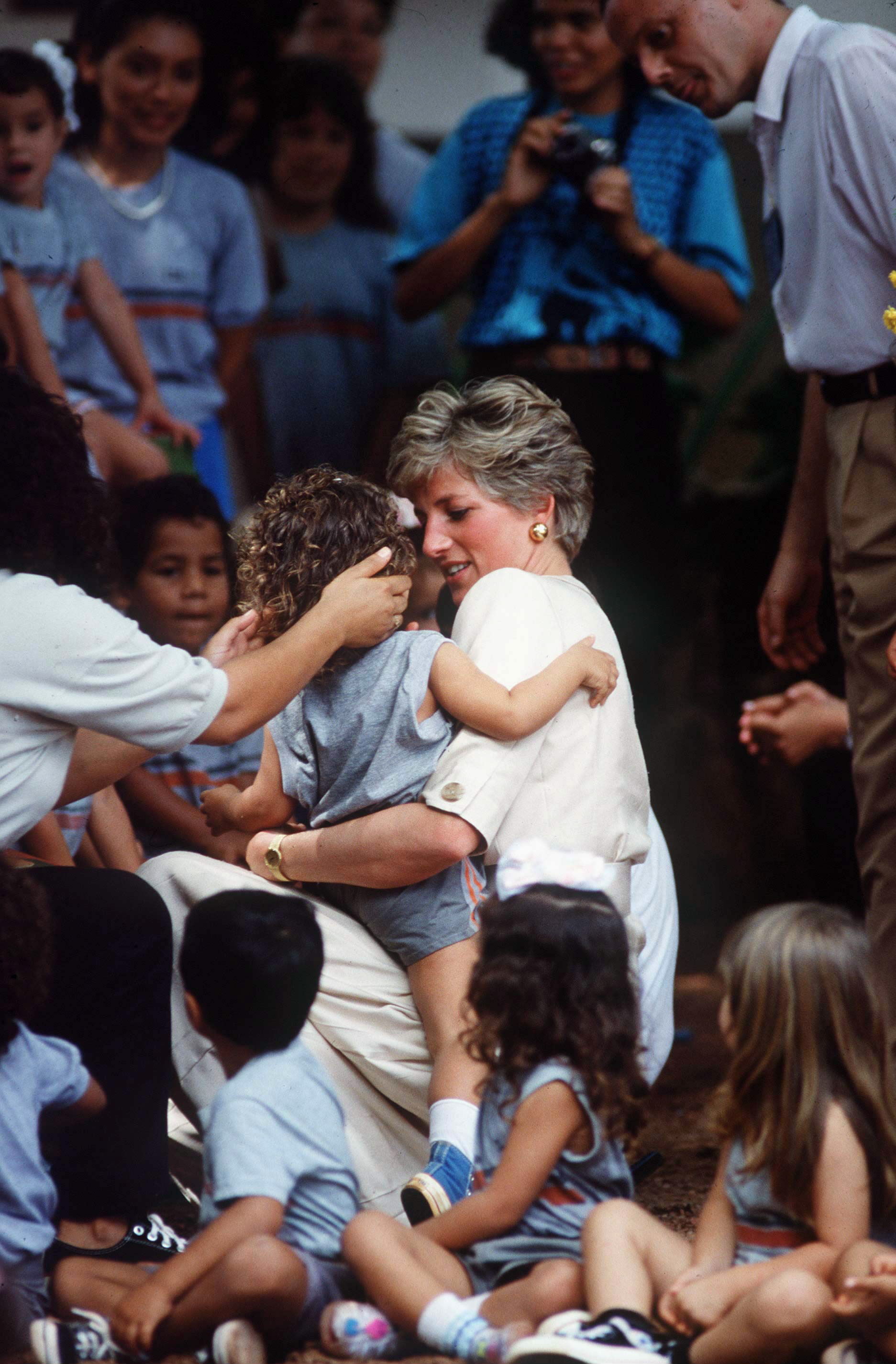 Princess Diana hugging a child in a group of kids at a school