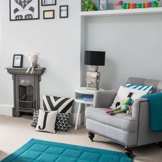 play room with grey wall and toys with cushion on armchair