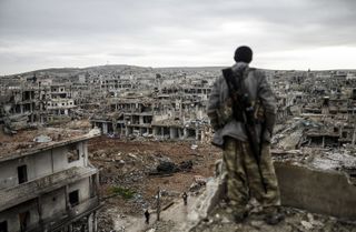 A marksman looks out over a destroyed Syrian city