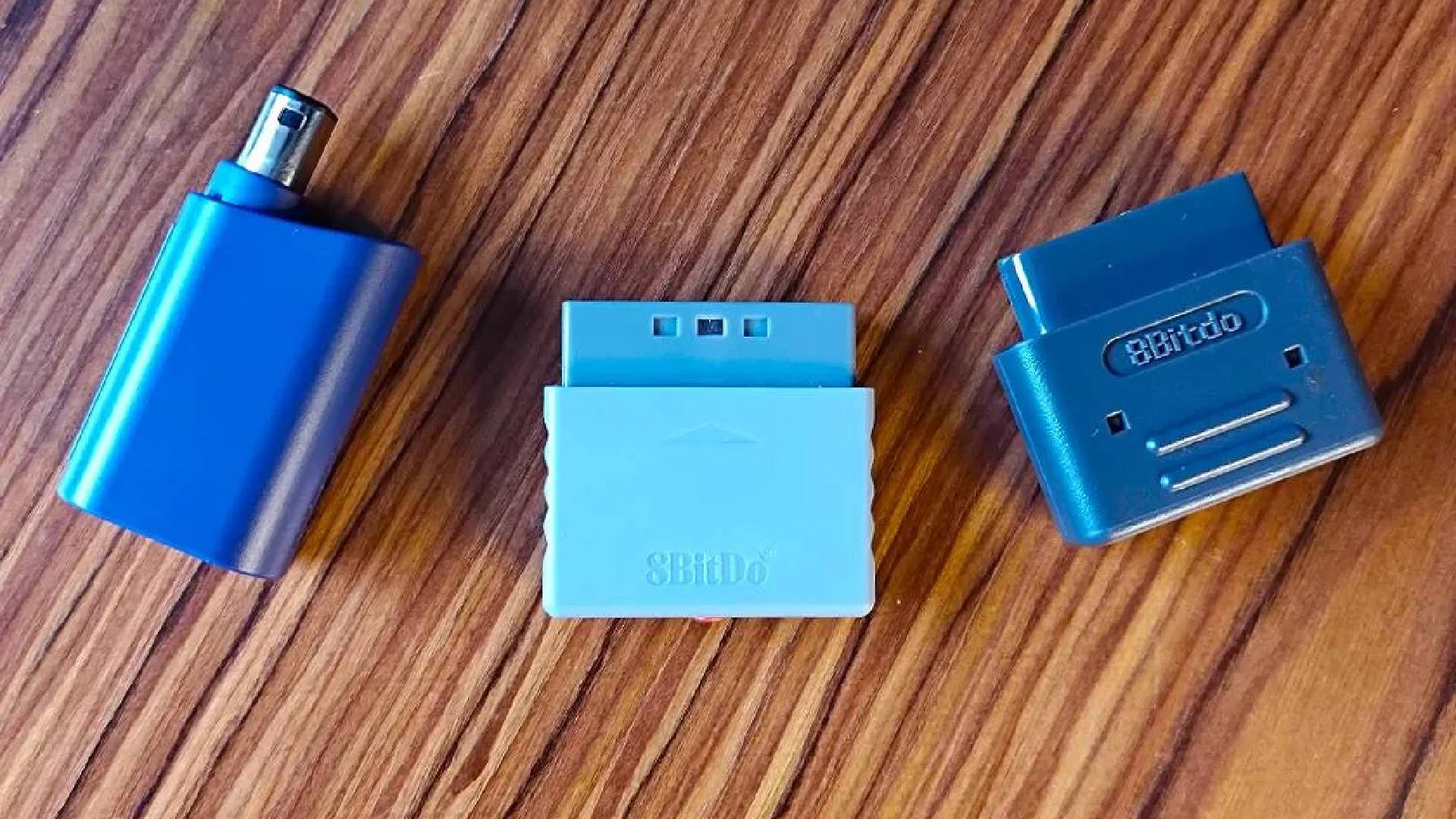 8Bitdo GameCube, PS1, and SNES Retro Receivers on a woodgrain table.