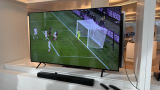 The LG B4 photographed on a white shelf with football on the screen