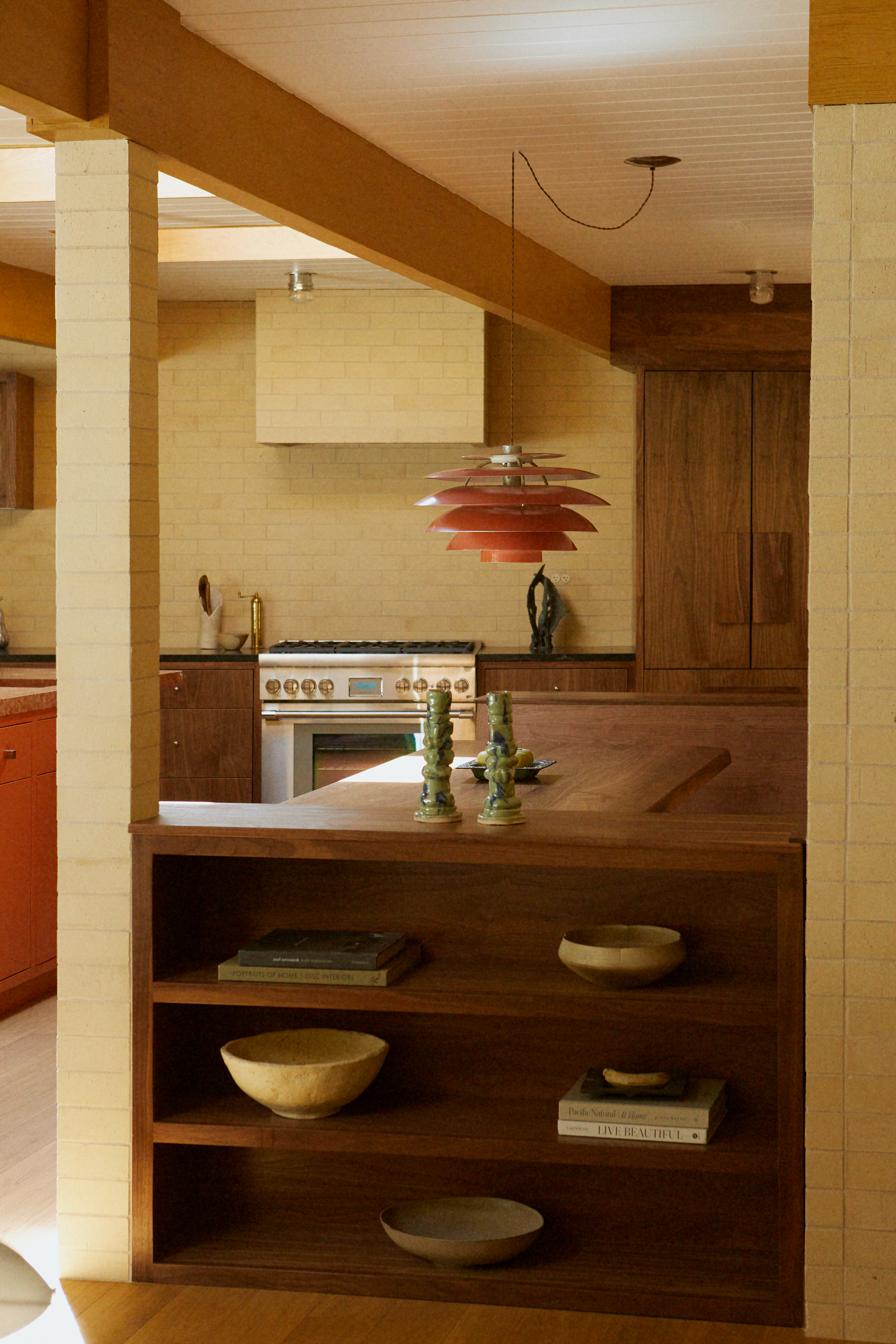 warm wooden kitchen with built-in shelving and brick walls
