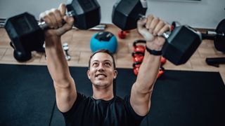 Man performing chest press with dumbbells in gym