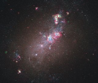 Galaxy NGC 4214 is dominated by a huge glowing cloud of hydrogen gas in which new stars are being born. A heart-shaped hollow — possibly galaxy NGC 4214’s most eye-catching feature — can be seen at the centre of this. 