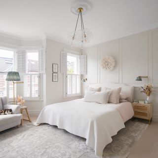white bedroom with pink bedding plantation shutters and glass pendant shade