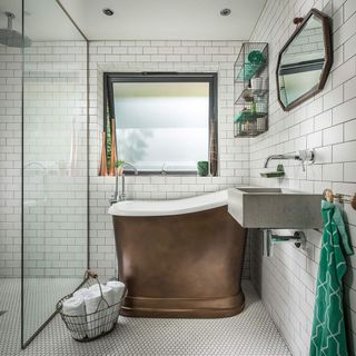 Bathroom with small copper freestanding bath, white brick wall tiles and white small honeycomb floor tiles