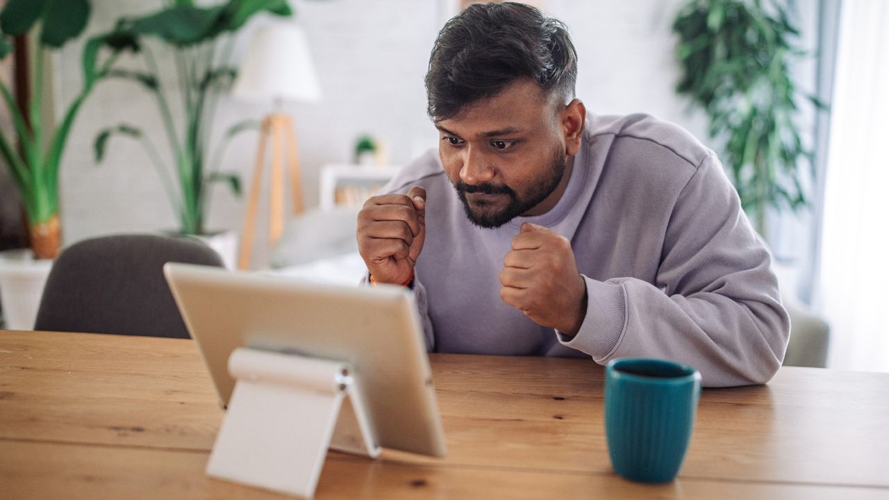 Man anxiously watching a sports game on his tablet, hoping for a win because he bet money on the outcome