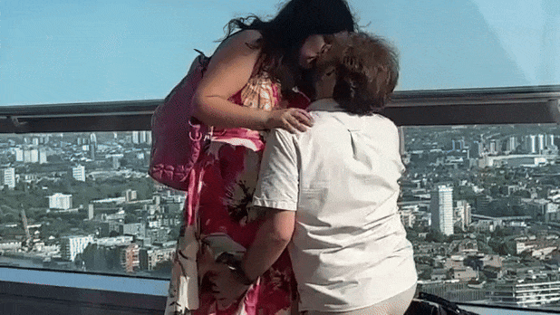 Ariane Sherine and Adam Juniper kissing with London skyline behind