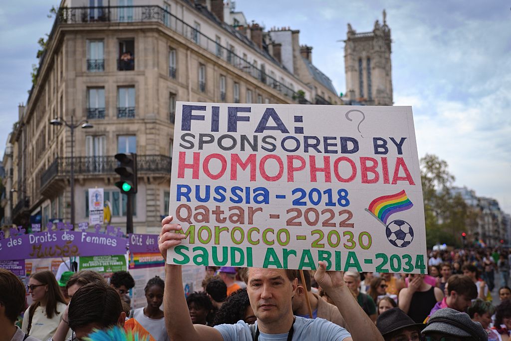 A Paris Pride participant holds up a sign criticising FIFA's choices of World Cup hosts