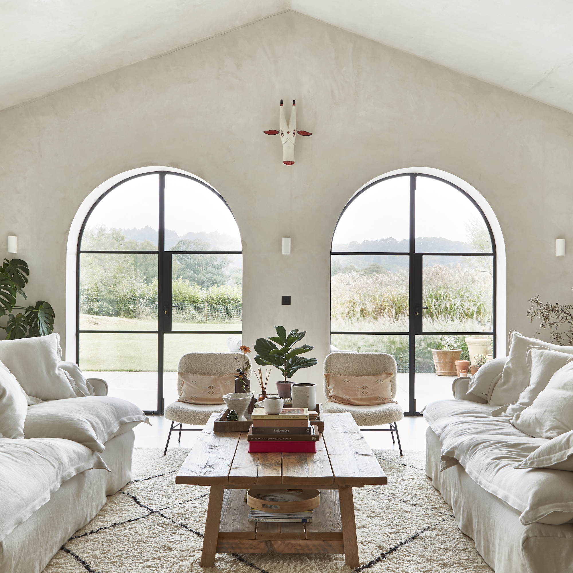 modern farmhouse living area with two white sofas facing opposite each other and coffee table on rug, with arched patio doors
