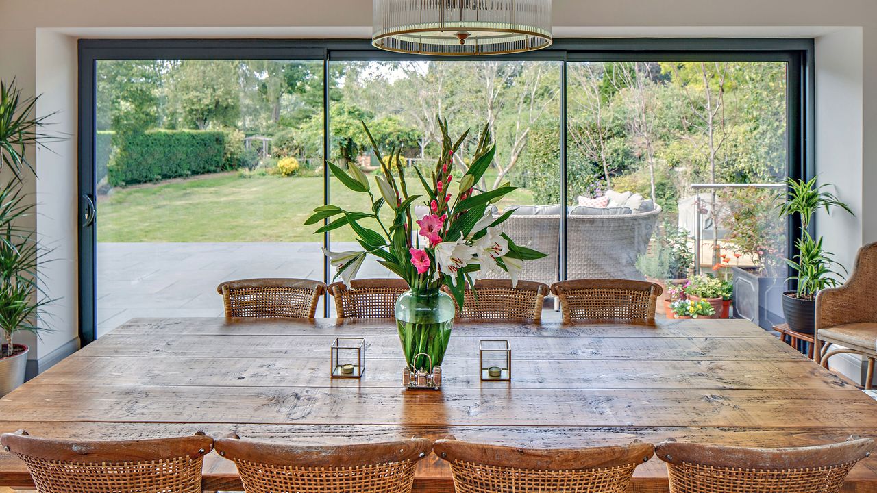 Wooden dining table in front of three panelled sliding glass doors